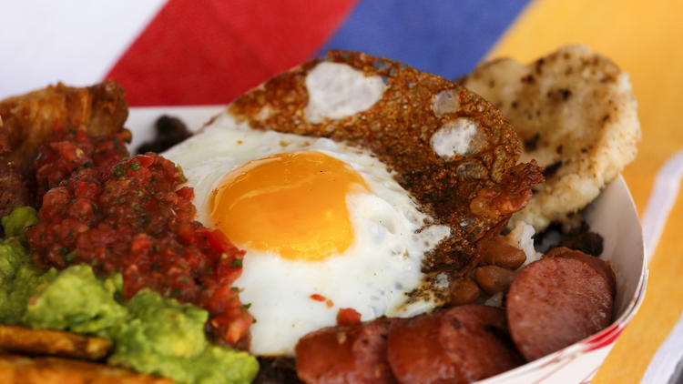 The Paisa Bowl is a protein-packed serving of pork belly, steak, sausage, beans, white rice, plantain, avocado, and an arepa topped with a fried egg, from the Cali Fresh food truck